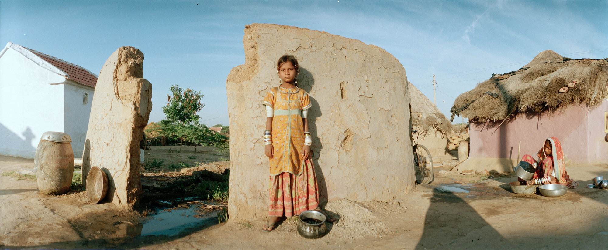 Young girl standing beside a mud wall in a village courtyard in Kutch, Gujarat.