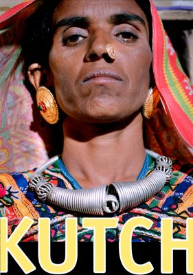 Exhibition poster for *Kutch – Journey to the Village of Ludia* featuring a close-up portrait of a woman from the Kutch desert in India, wearing traditional jewelry and colorful clothing. Poster design includes exhibition information for Magi Viljanen’s 1996 Helsinki exhibition.