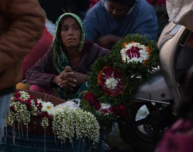 A flower seller sitting beside ceremonial floral decorations in Ahmedabad.