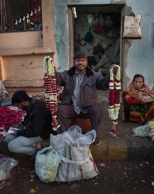 A flower vendor displaying rose and jasmine garlands in Ahmedabad.