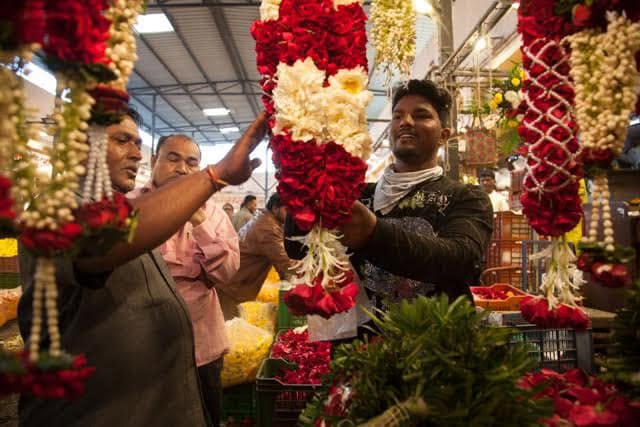 Traders inspecting flower garlands inside Ahmedabad flower market.